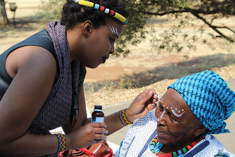 Lydia Mphatja (Oliewenhuis) decorating a participant of the Batho Oral History Project